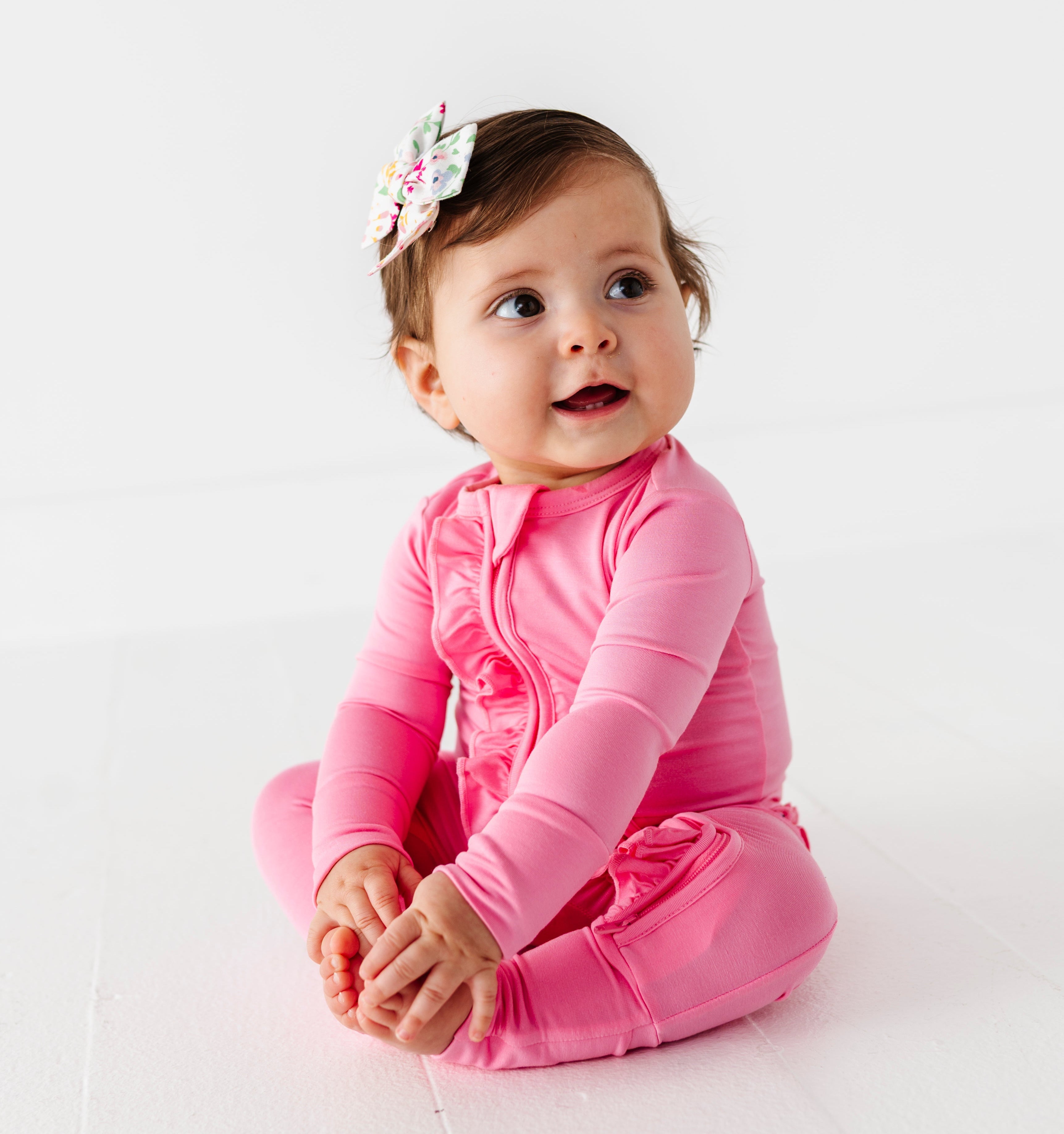 Baby in a bright pink bamboo zip romper on a white background